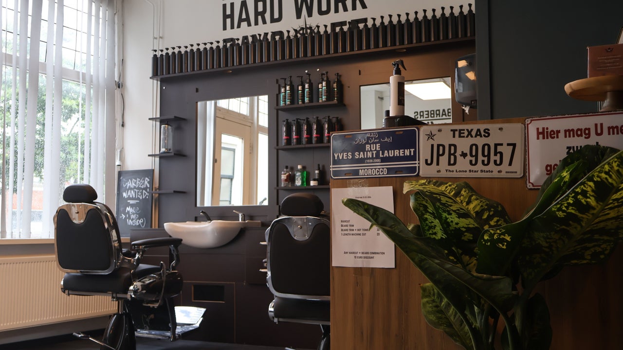 Het interieur van Zed's Barbershop met de kappersstoelen en de tekst Hard work pays off