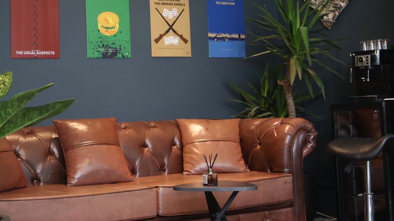 De wachtruimte met een bruine leren chesterfield en posters aan de muur