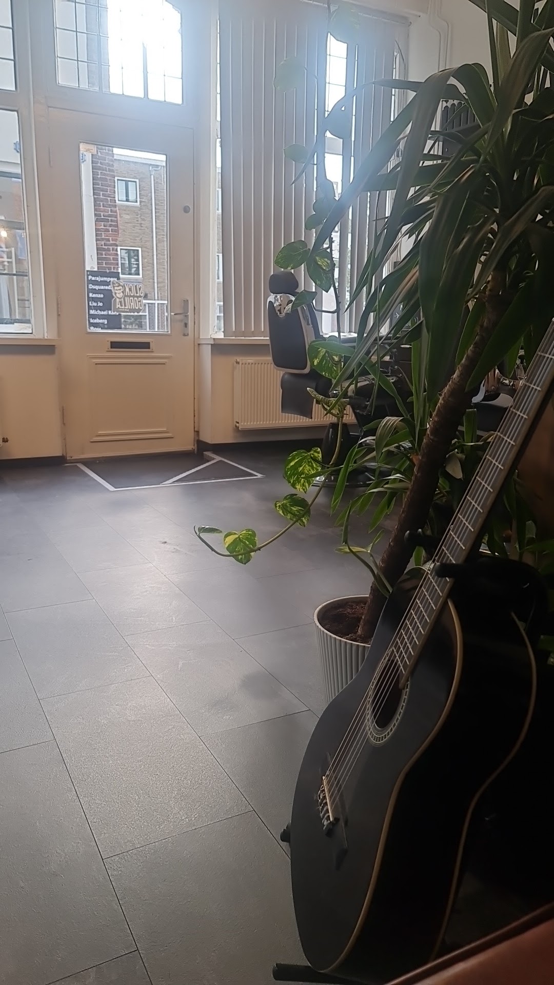De entree van de zaak met planten en een gitaar